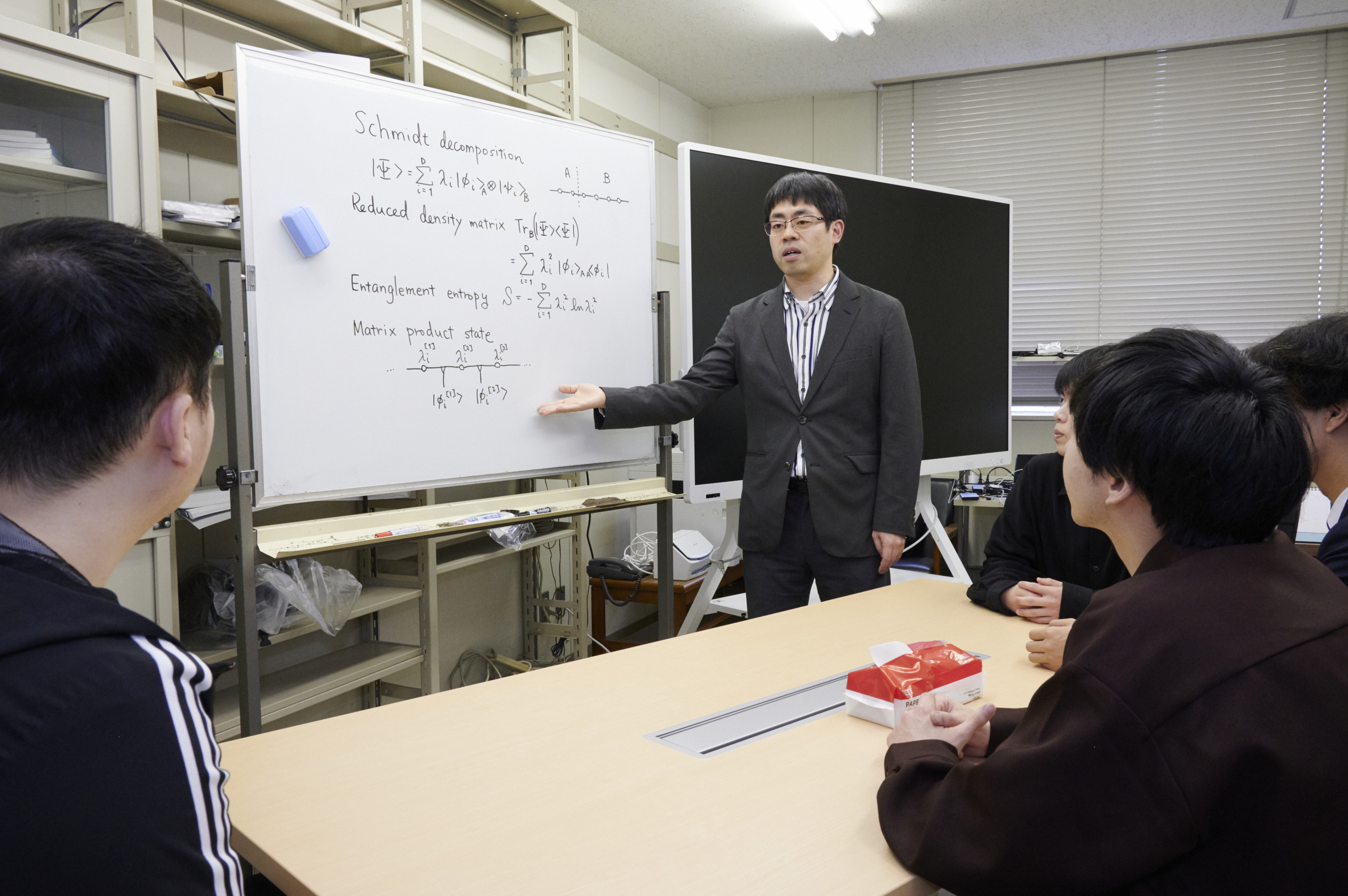 研究室のセミナーで説明している様子です。物理の理論系研究室では、本や論文を読んでその内容について説明するセミナー・輪講が定期的に行われます。
