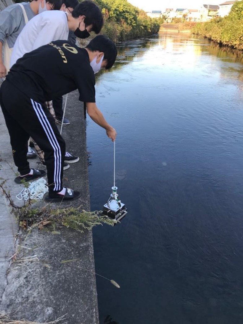 採泥器を用いて川底の泥を採取している様子。様々な環境から水や土などを採取して研究室に持ち帰り、その中にいる微生物を分離します。