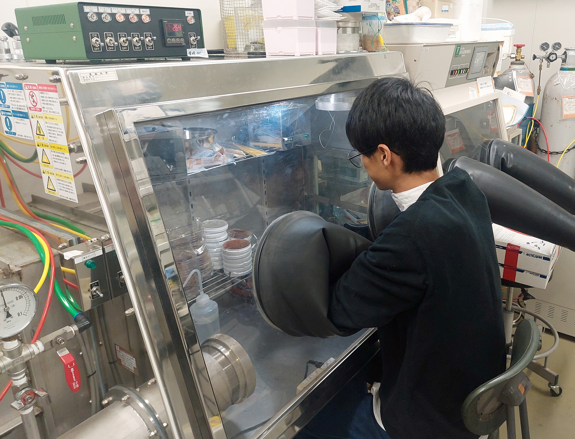 内側の酸素がない状態にする密閉された培養装置内で、微生物の培養準備をしています。