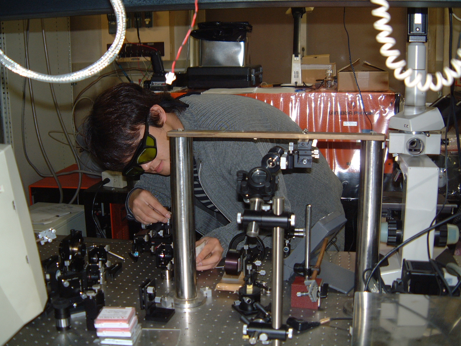 レーザー共振器から出力するレーザー光を調整している様子。研究を開始したばかりの学生時代の頃です。発振するレーザー光は近赤外波長で目に見えないために、特殊な紙を使って出力ビームを見ながらレーザー共振器を構成する鏡を調整しました。