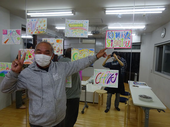 火曜日に運営している居場所での写真です。アーティストさん方に助けてもらいつつ、地元の方々と一緒にアートワークショップを行った後、暖かいご飯を食べています。新型コロナウィルスで閉室した期間もありましたが、感染に気を付けて再開しています。写っているのは地元のKさん。『ビッグイシュー』というホームレス支援の雑誌を毎日頑張って売っています。私たちの居場所にとってはなくてはならない「主（ぬし）」でもあります。