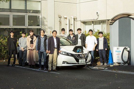 研究室メンバーとEVを囲んで。EVから建物側へ給電しています。