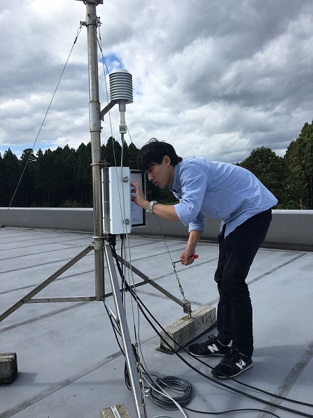 研究室の大学院生が大気観測施設屋上の気象測器の点検をしているところ