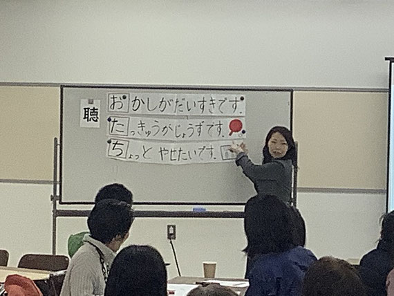 地域に住む外国人と日本人との交流会で，自己紹介ゲームの説明をしています。