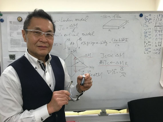 作製した高温超伝導膜 説明：左手に持っているものは超伝導薄膜を作るための原料溶液。この溶液を基板に塗布・熱処理（図２の装置）して超伝導膜を作製する。右手に持っているのは研究室で作製した超伝導薄膜。この薄膜は１平方センチメートルあたり480万アンペアもの電流を流す事ができる性能を持っている。