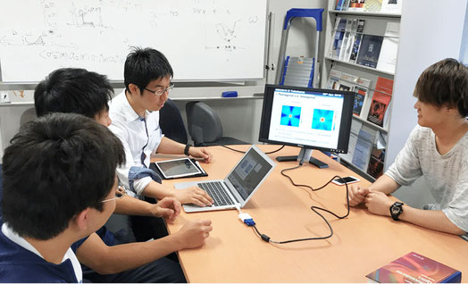 研究室で若手教員と学生のディスカッションです。ナノ微粒子集合体に光が当たった時の様子をシミュレーションした結果について議論しています。