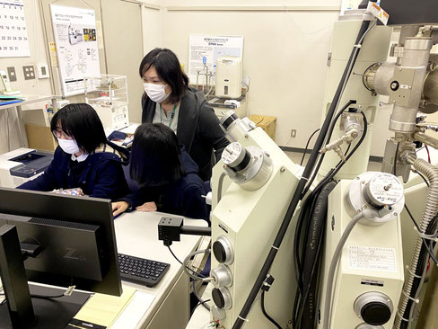 当研究室の学生の分析を指導しているところです。コロナ禍で、研究室でも全員常時マスクを着用しています。電子線マイクロプローブアナライザーという装置を使って鉱物の化学的特徴を明らかにしています。