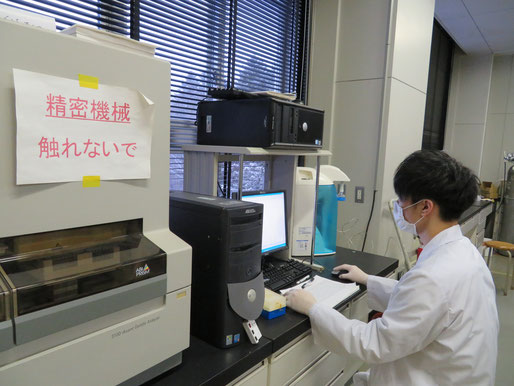 DNA 解析装置を使用中の学生（於：研究室）